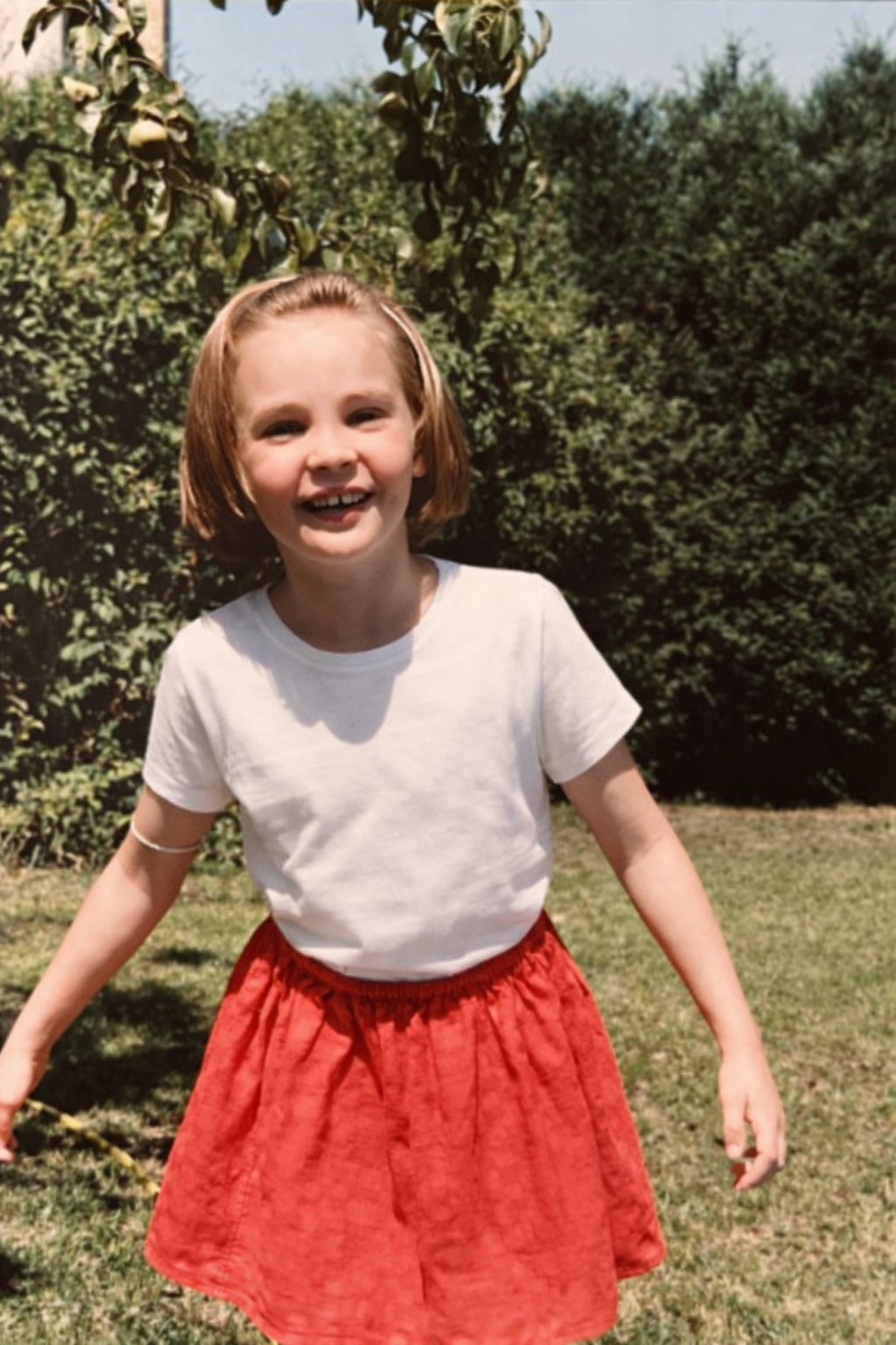 Une fille de 7 ans joue dans le jardin, elle sourit à la caméra